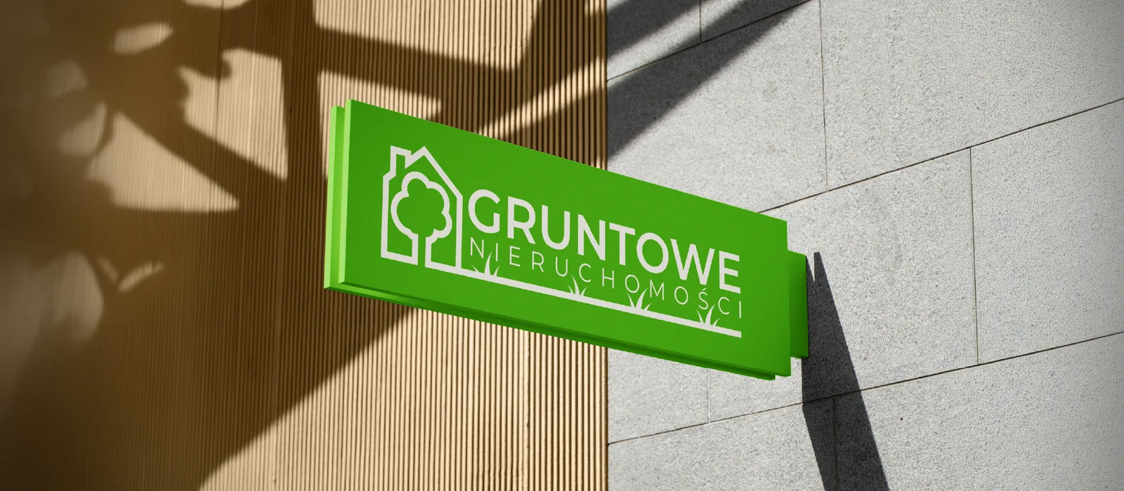 Szyld z logo Gruntowe Nieruchomości na elewacji budynku